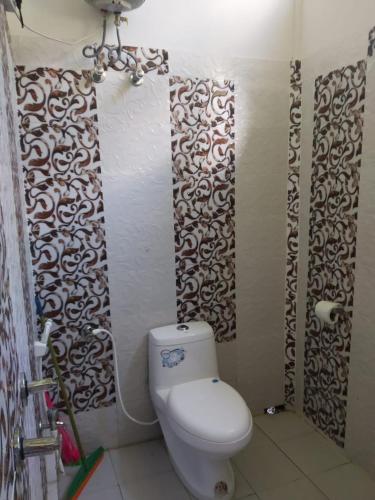 a bathroom with a toilet and a wall at Orange Orchard in Karsiyang