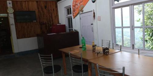 tavolo e sedie in una stanza con una grande finestra di Vamoose Orange Valley Sittong a Karsiyang