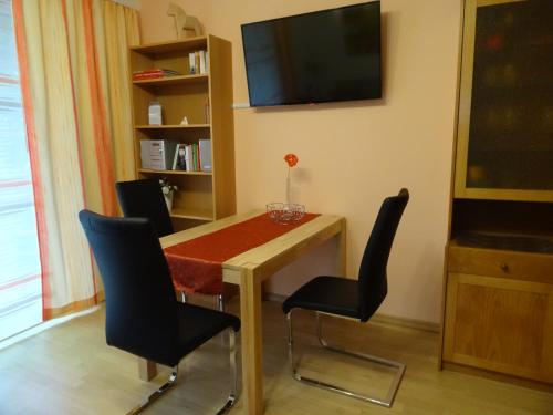 a room with a table with chairs and a television at Ferienwohnung Am Wildmeisterweg in Wernigerode