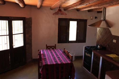 Habitación con mesa y cocina con ventanas. en Cabañas Maimará en Maimará