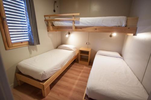 two bunk beds in a small room with a window at Camping Joan Bungalow Park in Cambrils