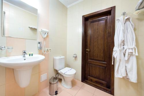 a bathroom with a sink and a toilet and a door at Villa Oselya in Kyiv