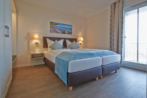 ベルガーエンデ・レートヴィッシュにあるAparthotel Waterkant Suites 2-33 mit Pool, Sauna und Meerblickのベッドルーム(大型ベッド1台、大きな窓付)
