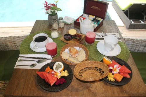 un tavolo di legno con piatti di cibo sopra di Maylie Bali Villa & Bungalows a Canggu