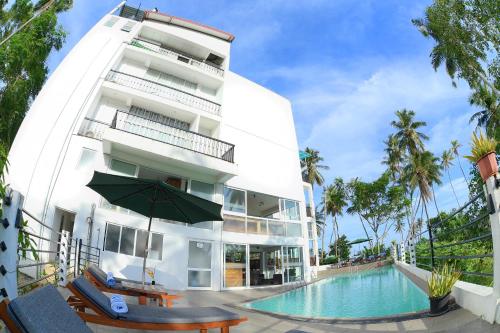 a white building with a swimming pool and a hotel at Sole Luna Resort & Spa in Tangalle