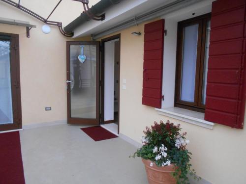 a building with red doors and a potted plant at LOCANDA RIGHETTO in Quinto di Treviso