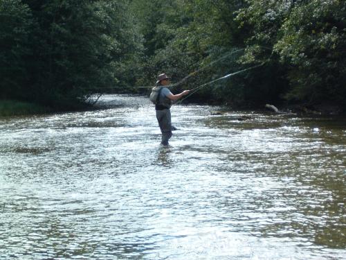 a man standing in a river holding a fishing rod at Tetter in Schladming