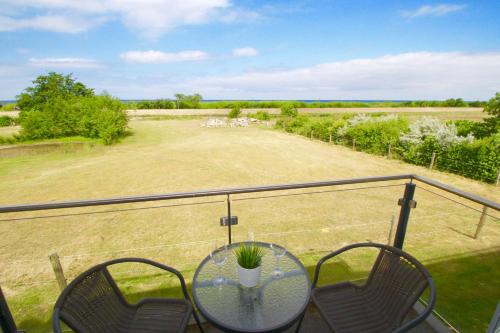 a table and chairs on a balcony with a field at Haus Calmsailing in Börgerende-Rethwisch