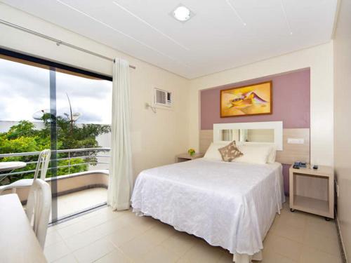 a bedroom with a bed and a balcony at Hotel Oceania in Eunápolis