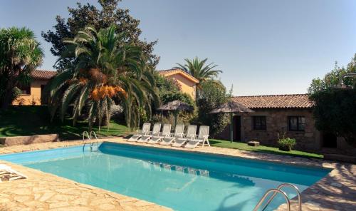 - une piscine avec des chaises et une maison dans l'établissement Apartamentos El Calambuco, à Villanueva de la Vera