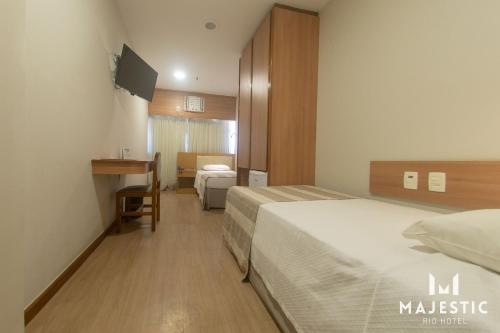 a hotel room with two beds and a desk at Majestic Rio Palace Hotel in Rio de Janeiro