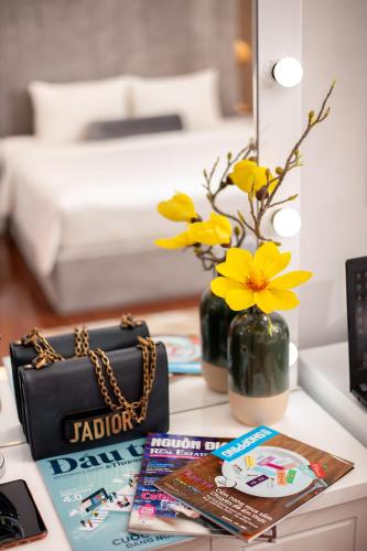 a table with a purse and a vase with yellow flowers at Adora Hotel in Ho Chi Minh City