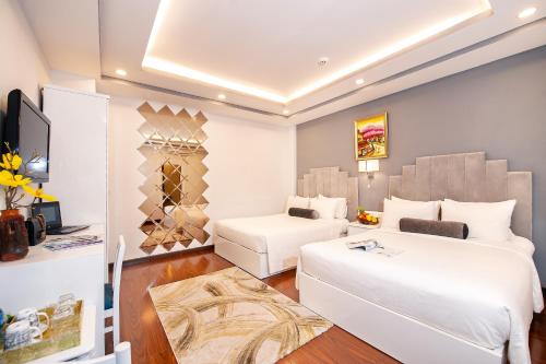a hotel room with two beds and a television at Adora Hotel in Ho Chi Minh City