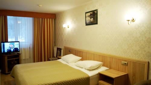 セルギエフ・ポサードにあるPansionat Voskhodのベッドとテレビが備わるホテルルームです。
