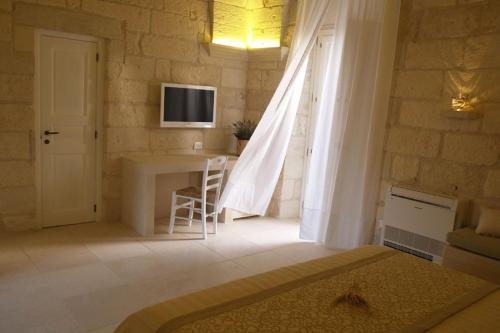 uma sala de estar com uma mesa e uma televisão na parede em Corte Dei Granai em Maglie
