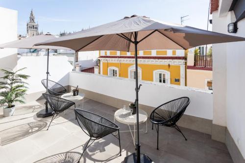 un patio con sillas y una sombrilla en el balcón en Oak & Sandstone Studio - Space Maison Apartments, en Sevilla