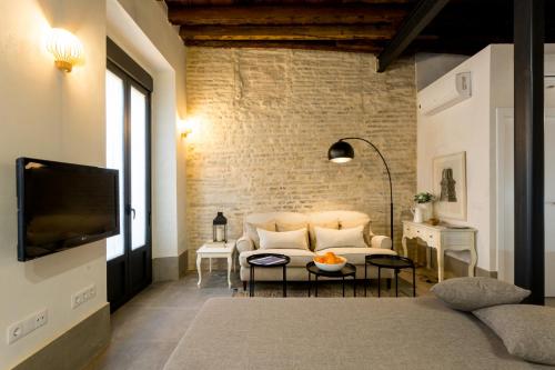 Una sala de estar con un sofá y un televisor. en Oak & Sandstone Studio - Space Maison Apartments, en Sevilla