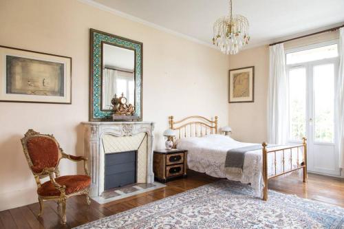 a bedroom with a bed and a fireplace and a mirror at Maison de Maître meulière in Neuilly-Plaisance