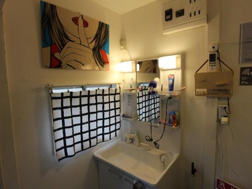 a bathroom with a sink and a painting on the wall at Shinjuku Welcome House inn in Tokyo