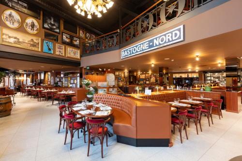 une salle à manger avec des tables et des chaises dans un restaurant dans l'établissement Hotel Leo Station, Villa et Annexes, à Bastogne