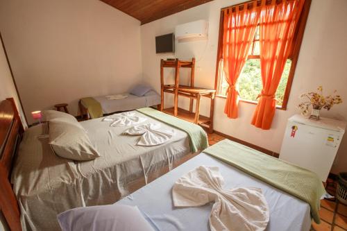 a bedroom with two beds and a window at Pousada Casa de Jorge in Lençóis