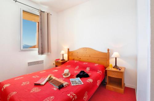 a bedroom with a red bed with a red blanket at Résidence Néméa Les Chalets Du Belvédère in Font-Romeu