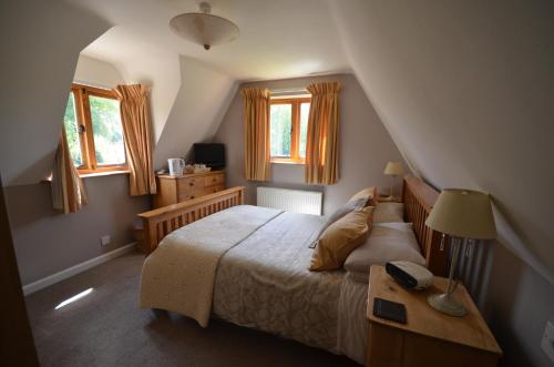 Schlafzimmer mit einem Bett mit einem Tisch und Fenstern in der Unterkunft Woodland Guesthouse in Stow on the Wold