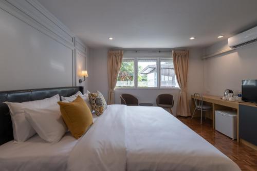 a bedroom with a large white bed and a desk at The Mellow Pillow Hotel @ Chiang Mai Gate in Chiang Mai