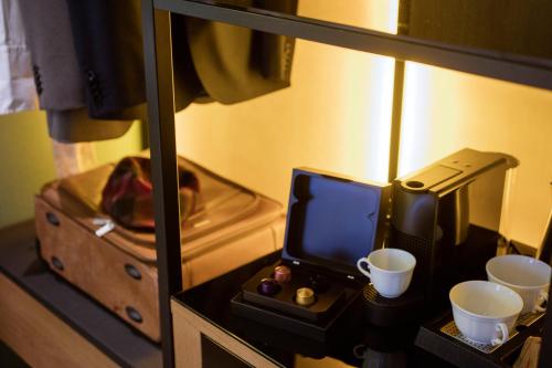フィレンツェにあるThe Frame Hotelのデスク、電話、カップが備わる客室です。