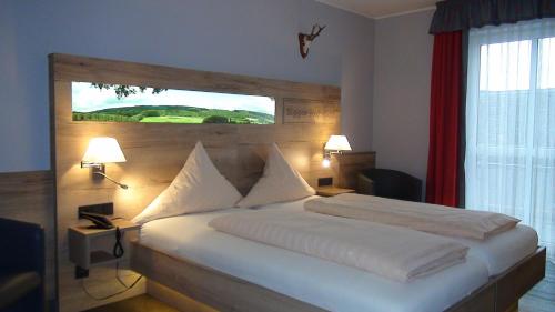 a bedroom with a large white bed with a window at Hotel Bigger Hof - Wirtshaus Platzhirsch am Jahnplatz in Olsberg