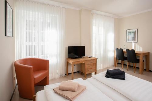 a room with two beds and a desk and a television at Hofgärtnerhaus in Dresden