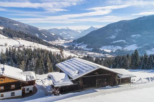 a cabin in the snow with mountains in the background at Bauernhütte Niedermaisgut in Eben im Pongau