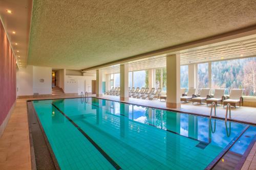 una grande piscina con sedie in un edificio di Diamant Spa Resort a Santa Cristina in Val Gardena
