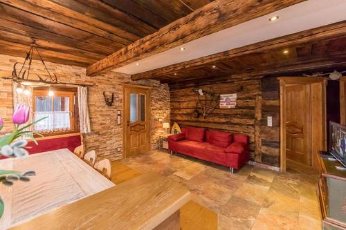 a living room with a red couch and wooden walls at Bauernhütte Niedermaisgut in Eben im Pongau