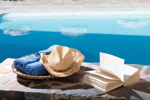 a hat and a book next to a swimming pool at Porto Sisi Hotel Apartments in Sissi