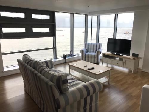 a living room with couches and a television with a view of the water at Edinburgh Western Harbour in Edinburgh