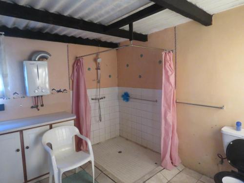 a bathroom with a shower with a sink and a toilet at Bare Foot Cottage in Hole in the Wall