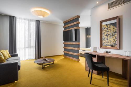 a room with a couch and a desk and a bed at Várda Sport Hotel in Kisvárda