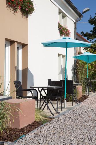 a table and chairs with umbrellas next to a building at ibis Haguenau Strasbourg Nord in Haguenau