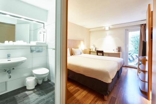 a bedroom with a bed and a bathroom with a sink at ibis Haguenau Strasbourg Nord in Haguenau