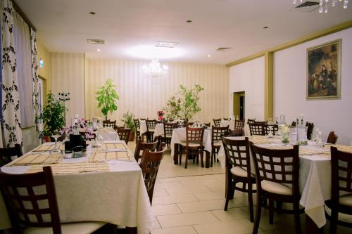 une salle à manger avec des tables, des chaises et un tissu de table blanc dans l'établissement Hotel Corona, à Drobeta-Turnu Severin