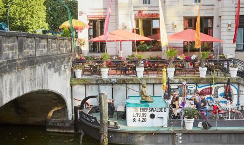 a boat docked next to a bridge with a restaurant at Living Hotel Großer Kurfürst in Berlin