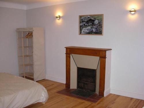 a living room with a fireplace and a bed at Maison Fouga in Cadéac