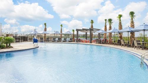 uma grande piscina com palmeiras e guarda-sóis em Hyatt Place Jacksonville St. Johns Town Center em Jacksonville