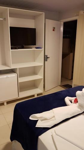 a bedroom with a bed with a tv and a closet at Pousada das Bromélias in Porto De Galinhas