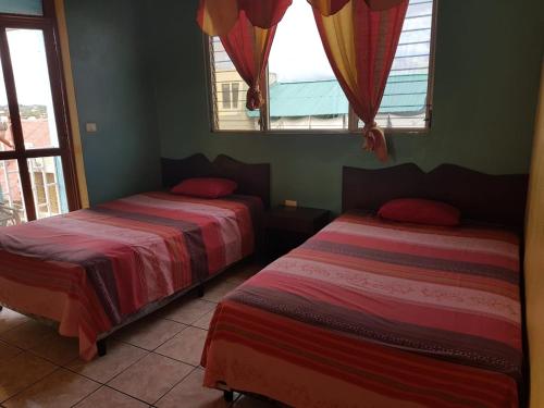 two beds in a room with two windows at Hotel Posada Tayazal in Flores
