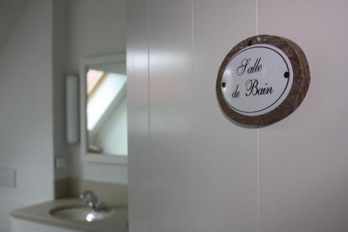 uma casa de banho com um espelho e uma placa na parede em Au grand large em Wimereux