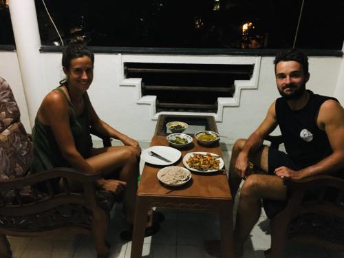 a man and a woman sitting at a table with food at Thalalla BnB in Talalla