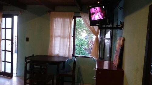 TV en una habitación con mesa y ventana en Belarmina posada del mar., en Aguas Dulces