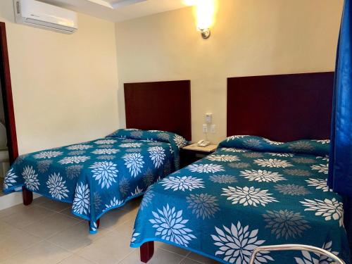 two beds in a room with blue walls at Hotel Cosmos in Tamasopo